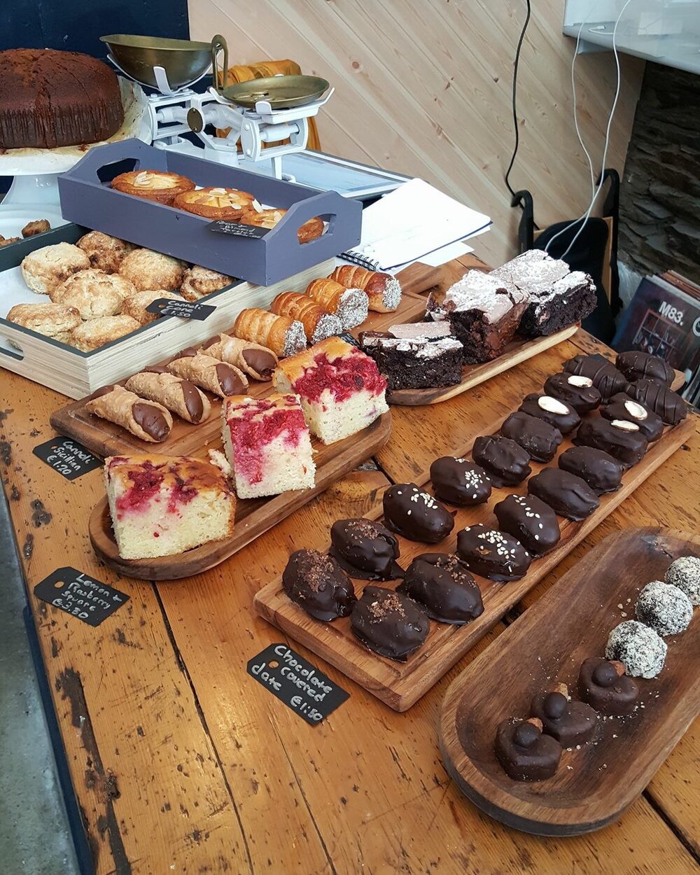 Cannoli, raspberry cake, brownies and chocolate-covered dates on wooden boards